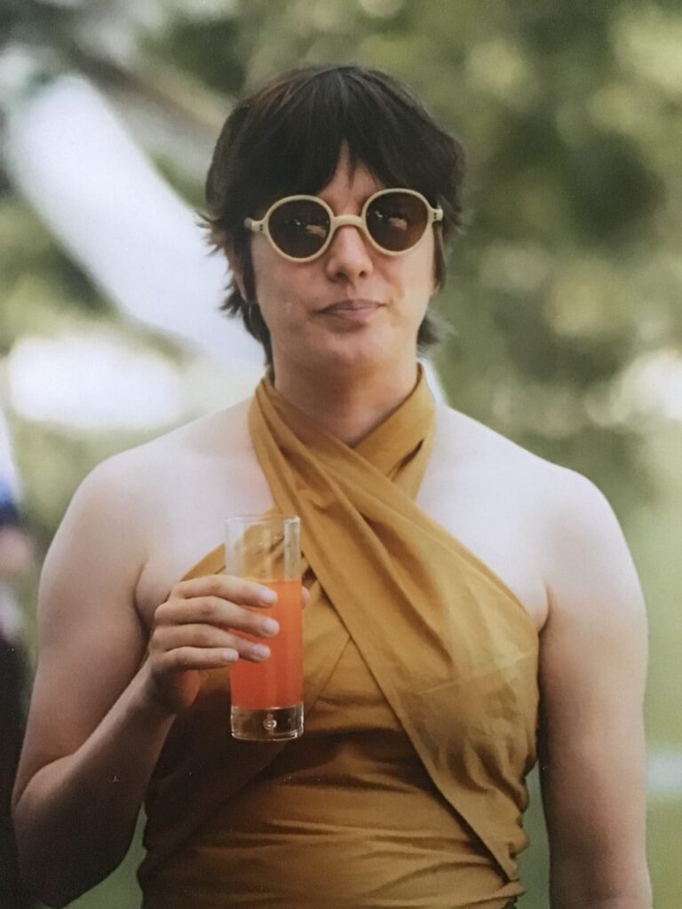 A handsome lady with a yellow selbstgenähtes Wickeloberteil trying to look intellectual in front of a blurred background.